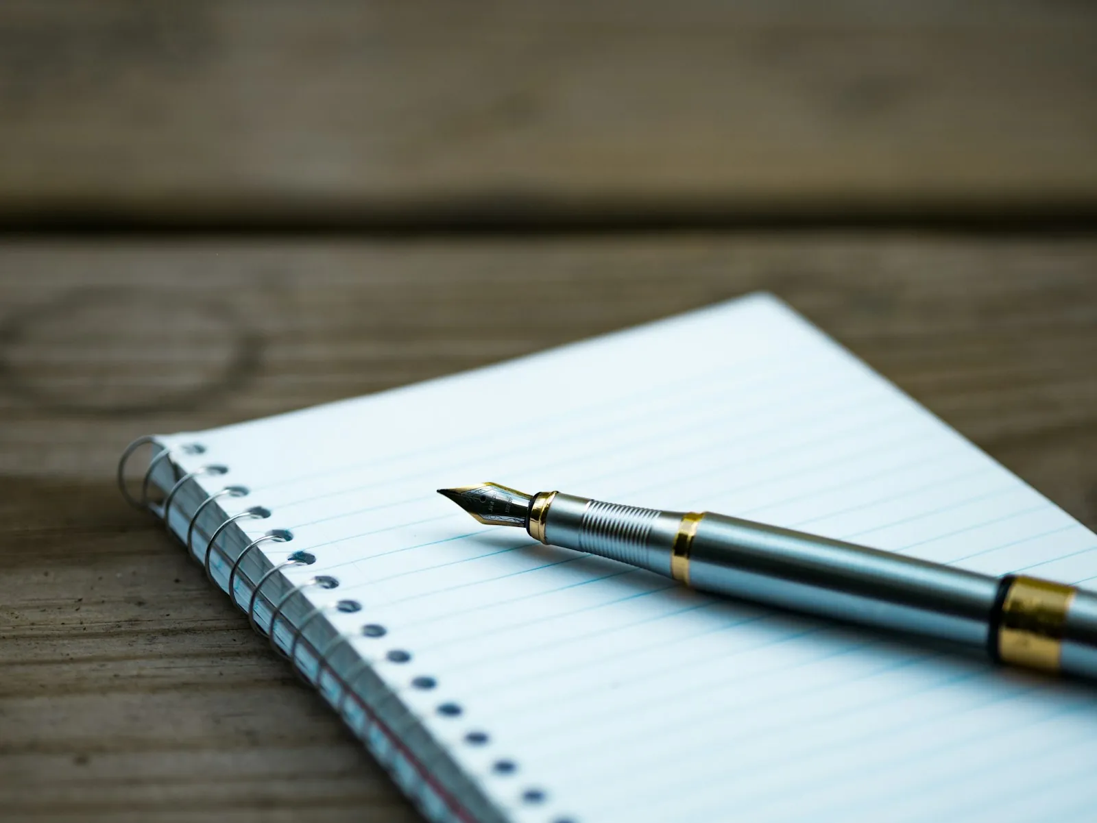 A tidy writing desk with notebooks, a fountain pen, and an ink bottle arranged neatly